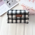 Gros plan d'une trousse de maquillage à carreaux noir et blanc avec logo en cuir - Laine Plaid Noir Gris