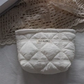 Detail of white quilted makeup bag with MAY RABBIT label on soft cotton lace background - Quilted Diamond White