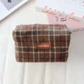 Gros plan d'une trousse à maquillage à carreaux marron avec étiquette en cuir sur laine - Laine Plaid Café