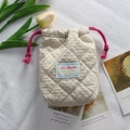 Macro shot of beige quilted fabric storage pouch with red drawstring and label detail - Quilted Pleated Khaki