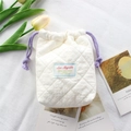 Close-up of quilted white cotton camera bag with purple drawstrings and embroidered logo - Quilted Pleated Beige White