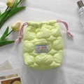 Detail of yellow heart-quilted drawstring pouch with soft fabric and embroidered logo tag - Quilted Cloud Yellow