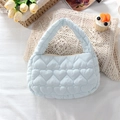 Close-up of light blue heart-quilted fabric handbag with zip closure on a white table - Quilted Large Heart Light Blue