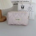 Close-up of pink quilted cosmetic bag with heart embroidery and brand logo label - Quilted Large Heart Light Pink