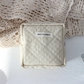 Detailed close-up of a quilted cream makeup bag with May Rabbit label on a lace fabric - Quilted Pleated Khaki