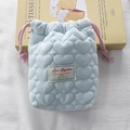 Close-up of soft blue quilted heart camera bag with pink drawstring and woven label - Blue Crepe Heart