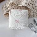 Detailed view of quilted white cosmetic bag with pink bow embroidery and branded label - Pink Embroidered Bow