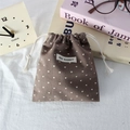 Detailed view of the brown drawstring bag with heart prints and a stitched fabric label - Coffee Brown with Off-White Hearts