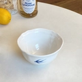 Detailansicht einer weißen Keramikschale mit Wellenrand und blauen Vogelmotiven auf dem Tisch - 4,5 Zoll Reisschüssel