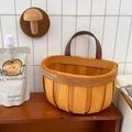Dettaglio di cesto a muro in legno intrecciato con manico in pelle e testo decorativo - Grande