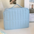 Close-up of light blue vertical quilted cosmetic bag with top handle and zipper - Blue