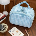 Detailed view of blue checkered quilted makeup bag with double zippers on wooden table - Blue Plaid