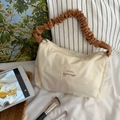 Dettaglio della texture a coste e del manico marrone arricciato su borsa beige - Contrasto Beige e Marrone