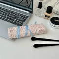Close-up of floral makeup brush roll bag with ribbon tie on a stylish vanity desk - Floral