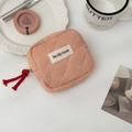 Detail of orange gingham quilted makeup bag with red tassel zipper and brand label - Orange Check