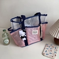 Dettaglio della borsa da spiaggia in rete rosa con manici blu e un piccolo portachiavi - Rosa