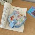 Detailansicht einer Mini-Stoffgeldbörse mit Bärenmuster auf einem offenen Buch - Babyblau