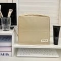 Borsa da toilette in tessuto beige in piedi sulla scrivania con manico e pennelli trucco - Beige