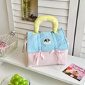 Detalle del neceser acolchado con lazos rosas y asa amarilla con el texto Lucky - Azul y Rosa