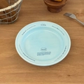 Detailopname van een lichtblauw keramisch bord met blauwe letters op een houten tafel - 7 inch rond bord