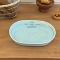 Vue de dessus d'un bol à salade ovale en céramique bleu clair avec typographie sur bois - Assiette ovale de 8 pouces