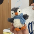 Détail d'un porte-clés pingouin en peluche avec écharpe bleue et pieds orange - Pingouin à écharpe bleue