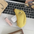 Draufsicht auf eine bananenförmige Geldbörse mit Lippenstift und kabellosen Kopfhörern - Banane