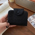 Close-up of black bubble textured fabric coin purse with round button in a retro setting - Black