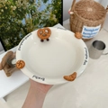 Detail showing embossed ceramic plate with croissant and pretzel patterns on cream surface - 8.5 Inch Plate