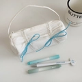 Close-up of a white pleated pencil case with blue ribbon bows and zipper handle - White