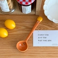 Detail eines süßen orangen Keramiklöffels mit Smile-Muster auf warmem Holztisch - Ananasbrötchen