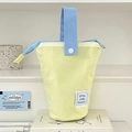 Dettaglio dell'astuccio in tela gialla con manici blu su uno scaffale bianco - Formaggio / Giallo