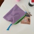 Detail der lila karierten Canvas-Tasche mit grünem Reißverschluss und blauem Quastenanhänger - Violettes Karo