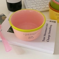 Detailed view of ceramic dog bowl with pink finish and green rim on a desk - Pink