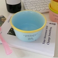 Close-up of a blue ceramic dog bowl with yellow rim on a cozy desk setup - Blue