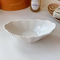 Close-up of a white ceramic bowl with beaded edges and irregular pearl relief design - Oval Bowl / Cream