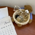 Detail of handmade woven bear storage basket holding glasses and perfume on desk - M