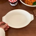 Nahaufnahme der weißen ovalen Auflaufform aus Keramik mit Griffen auf einem Holztisch - Weißer Ovaler Tiefer Teller