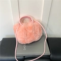 Borsa a tracolla in ecopelliccia rosa con manico intrecciato su fondo di libro - Rosa