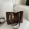 Sac cabas marron foncé avec surpiqûres blanches et foulard en soie sur un canapé - Brun Foncé