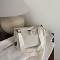 Borsa a tracolla cilindrica in nylon beige mostrata in un ambiente di vita quotidiana - Bianco