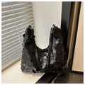 Dettaglio macro di grandi paillettes nere sulla borsa con effetti di luce scintillanti - Nero
