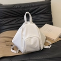 Minimalist white geometric triangle backpack with front pocket on a black leather sofa - White