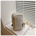 Detail of beige wrinkled texture crossbody chest bag placed on a white book decor - White