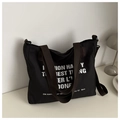 Dettaglio della borsa tote nera in nylon con manici marroni e scritte bianche artistiche - Nero
