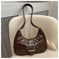 Detalle de bolso hobo marrón oscuro con cremalleras plateadas sobre una silla - Marrón