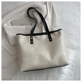 Detail of off-white faux leather tote bag showing textured surface and black shoulder straps - White