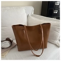 Brown vintage tote bag displayed on white sofa with casual daily life accessories - Tan