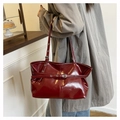 Détail du sac sous l'aisselle en cuir verni rouge foncé avec boucle métal sur bandoulière - Rouge