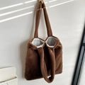 Detailed view of brown plush tote bag texture with natural sunlight shadow on wall - Brown